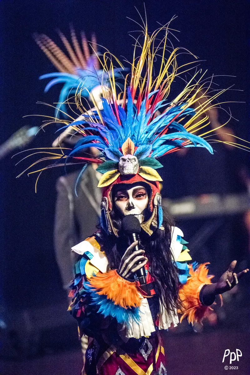 Mamselle Ruiz en costume et grande coiffe de plumes colorées