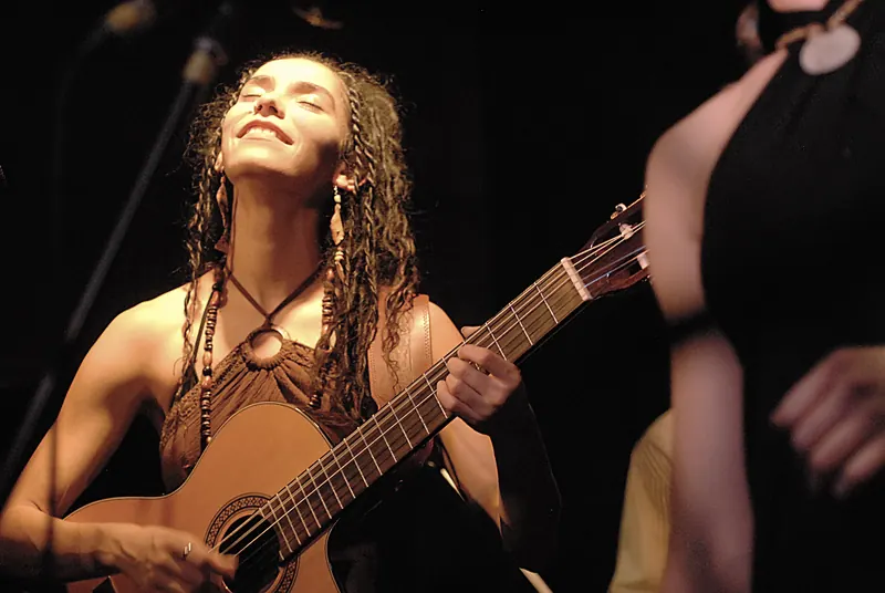 Mamselle Ruiz sourit en jouant de la guitare