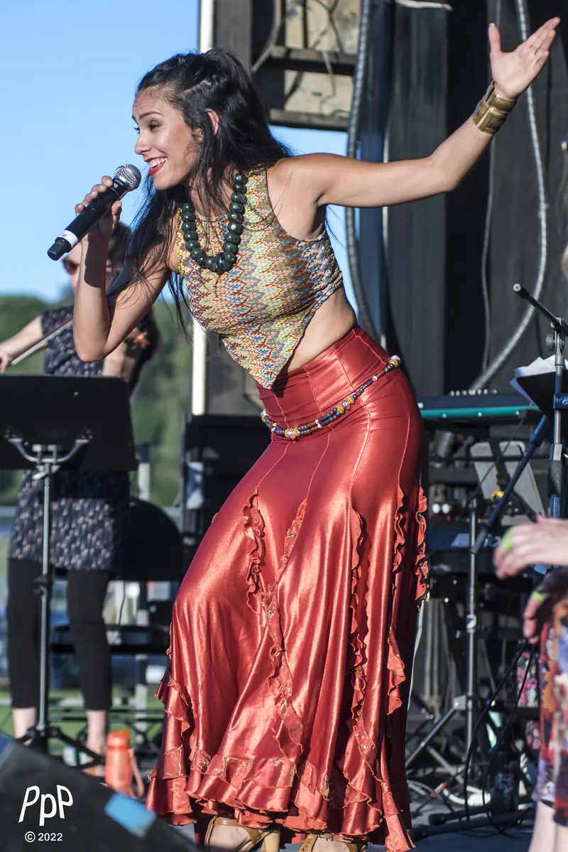 Mamselle Ruiz chante en jupe rouge sur une scène en plein air